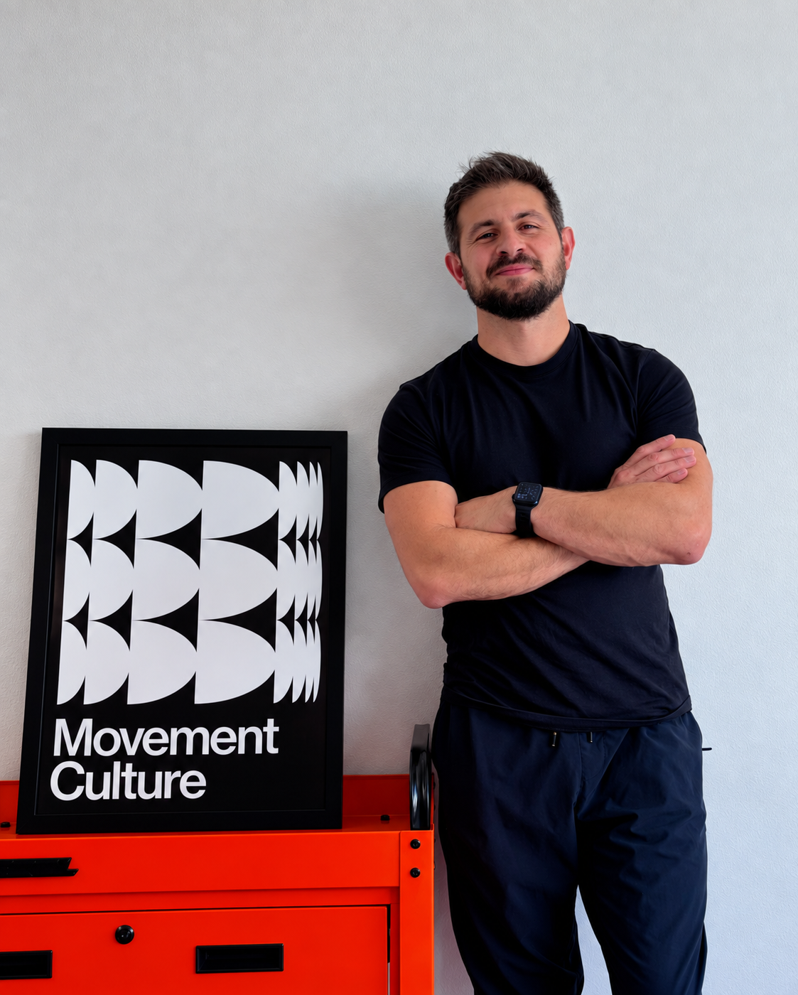 Dr. Shahan Awakimian standing beside Movement Culture artwork and an orange cabinet
